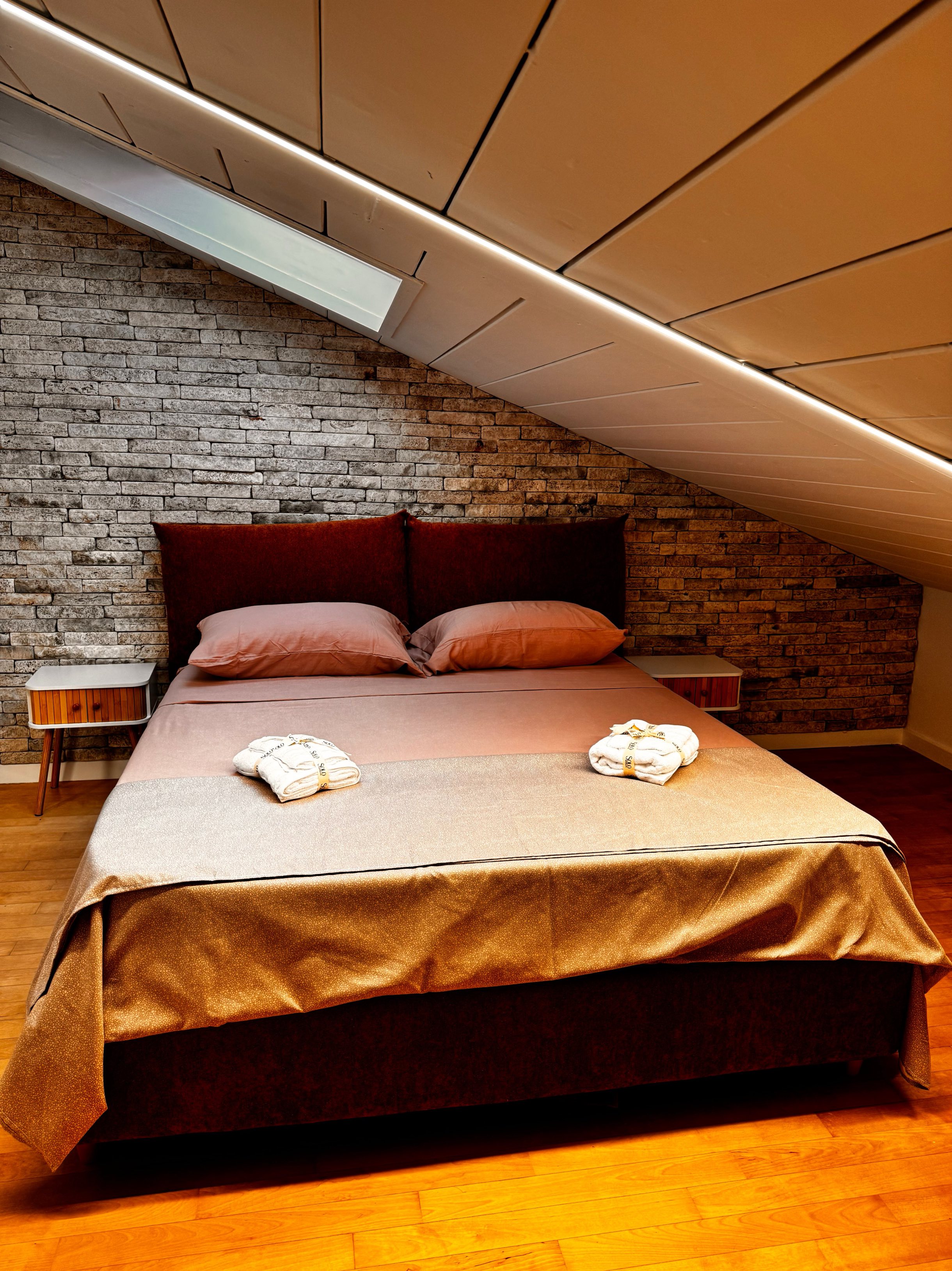 Camera da letto con testata in pietra e biancheria calda